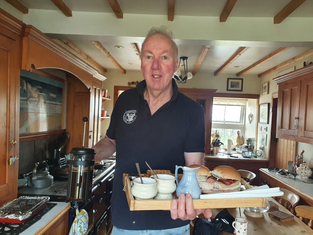 Man carrying breakfast tray with mugs and jug