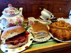 Teapot, roll and bacon, croissants and cups