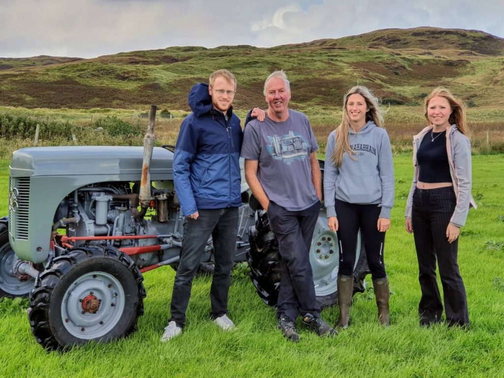 People stood beside an old grey tractor