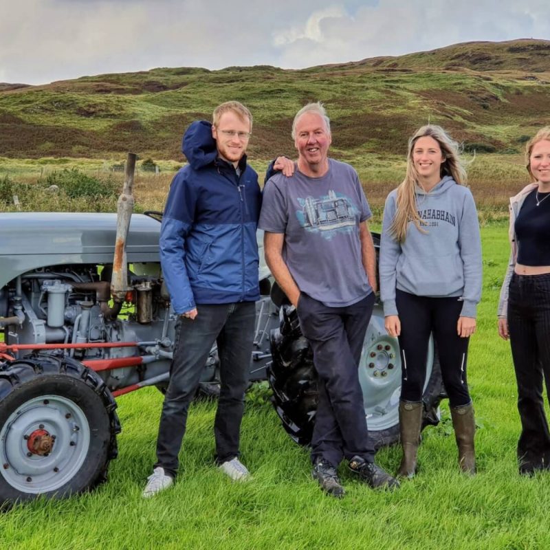 People stood beside an old grey tractor