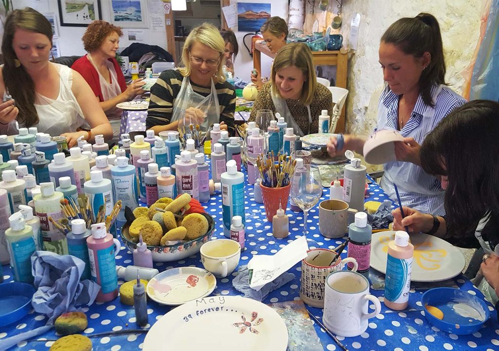 A group of people enjoying a pottery painting experience at Persabus Pottery