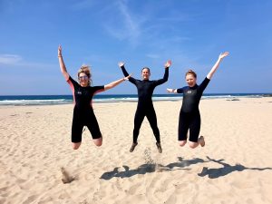 Three people jumping in the air on sandy beach
