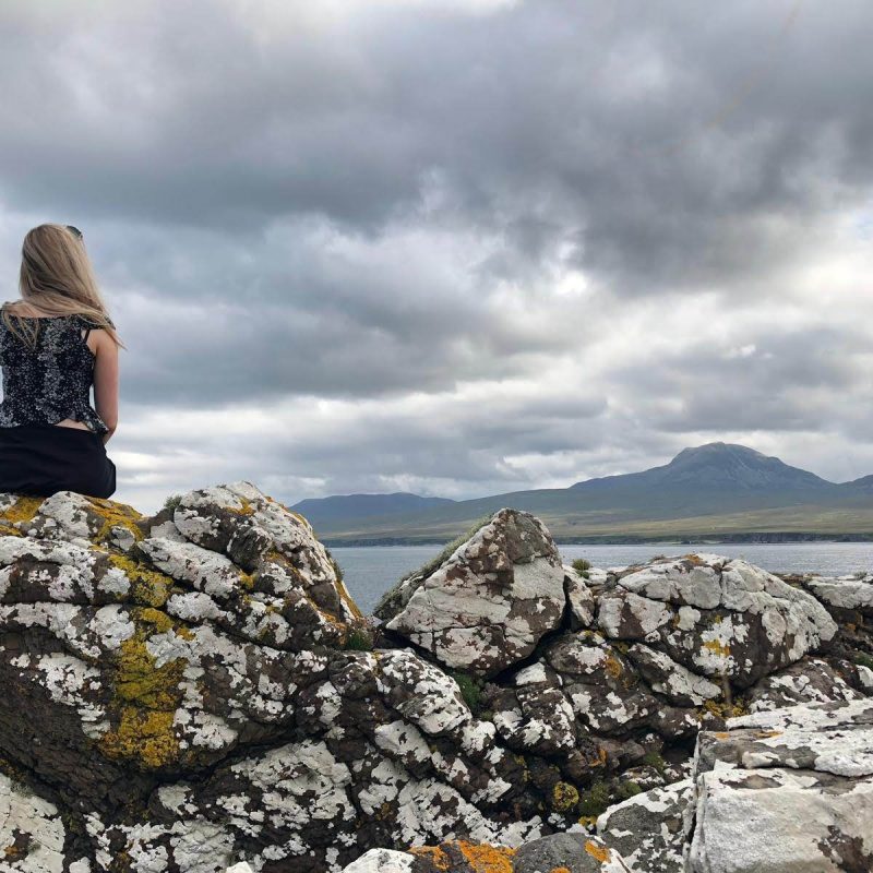 Person sat on rock looking out to sea