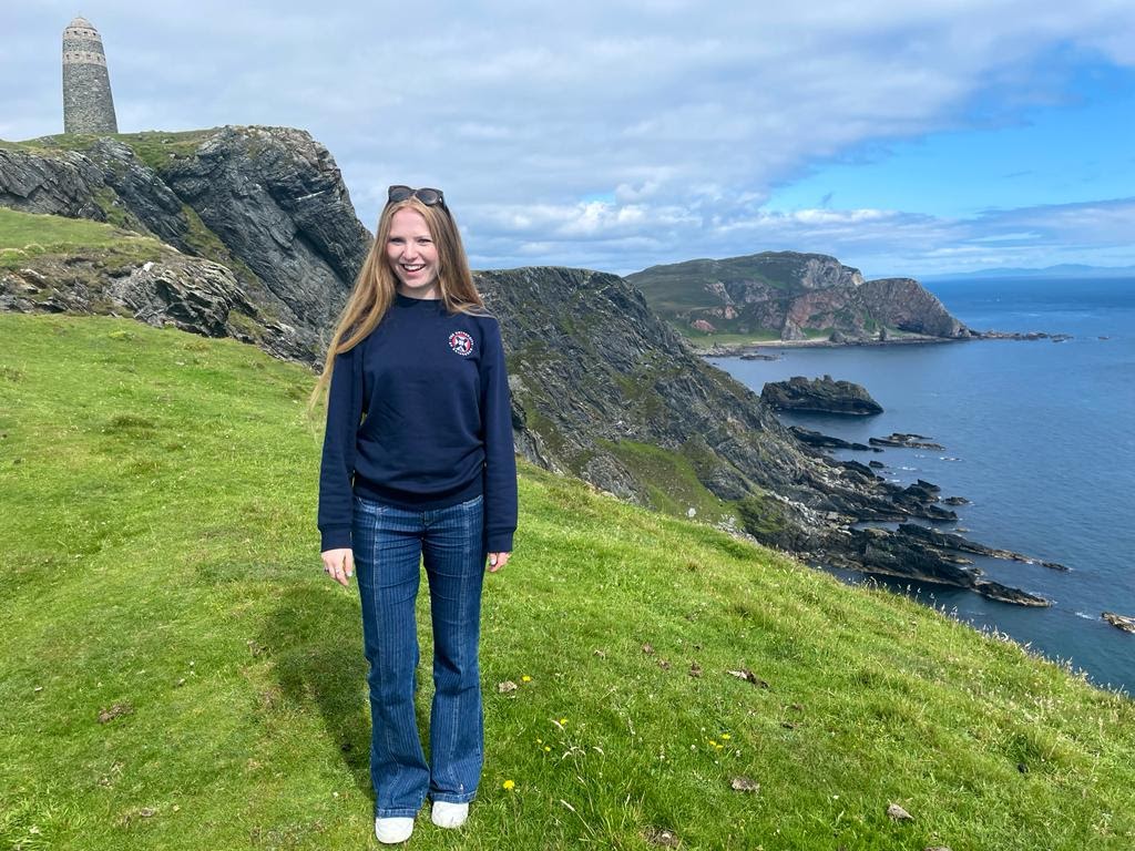 Girl standing by sea with monument in background