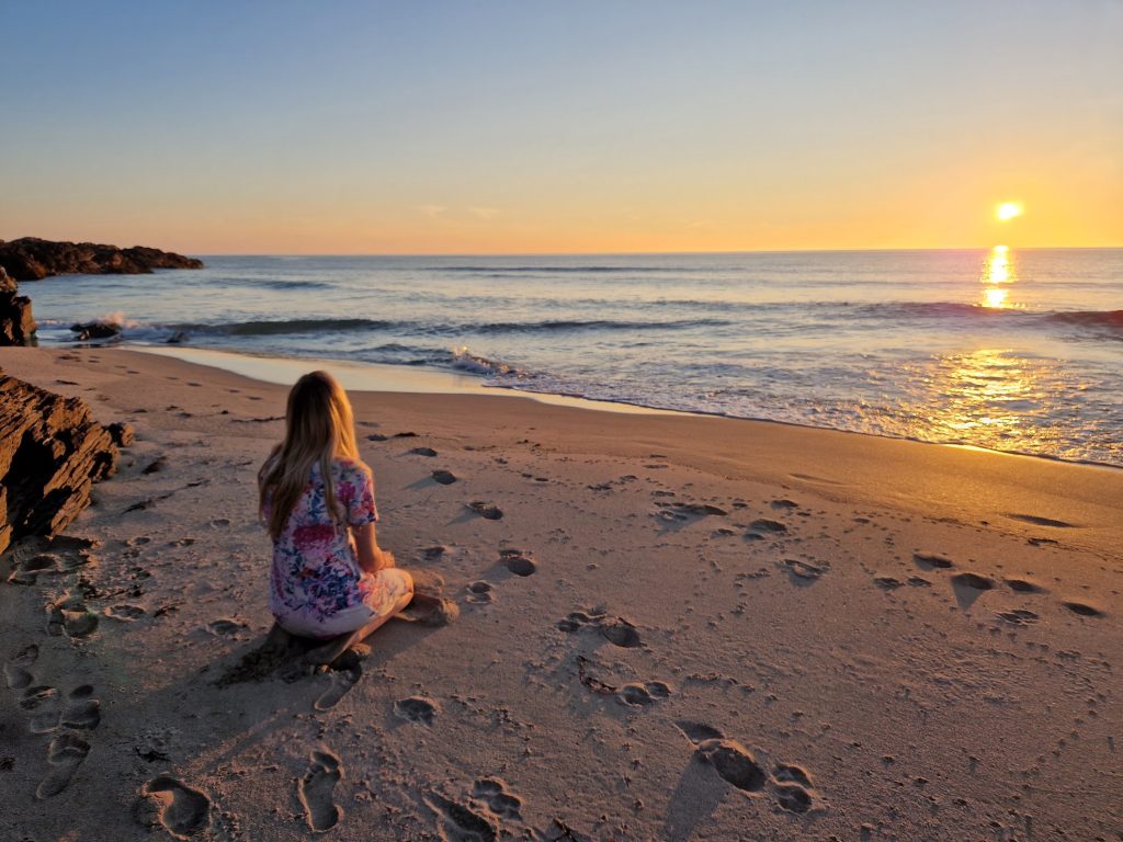 Girl sat on beach watching sunset