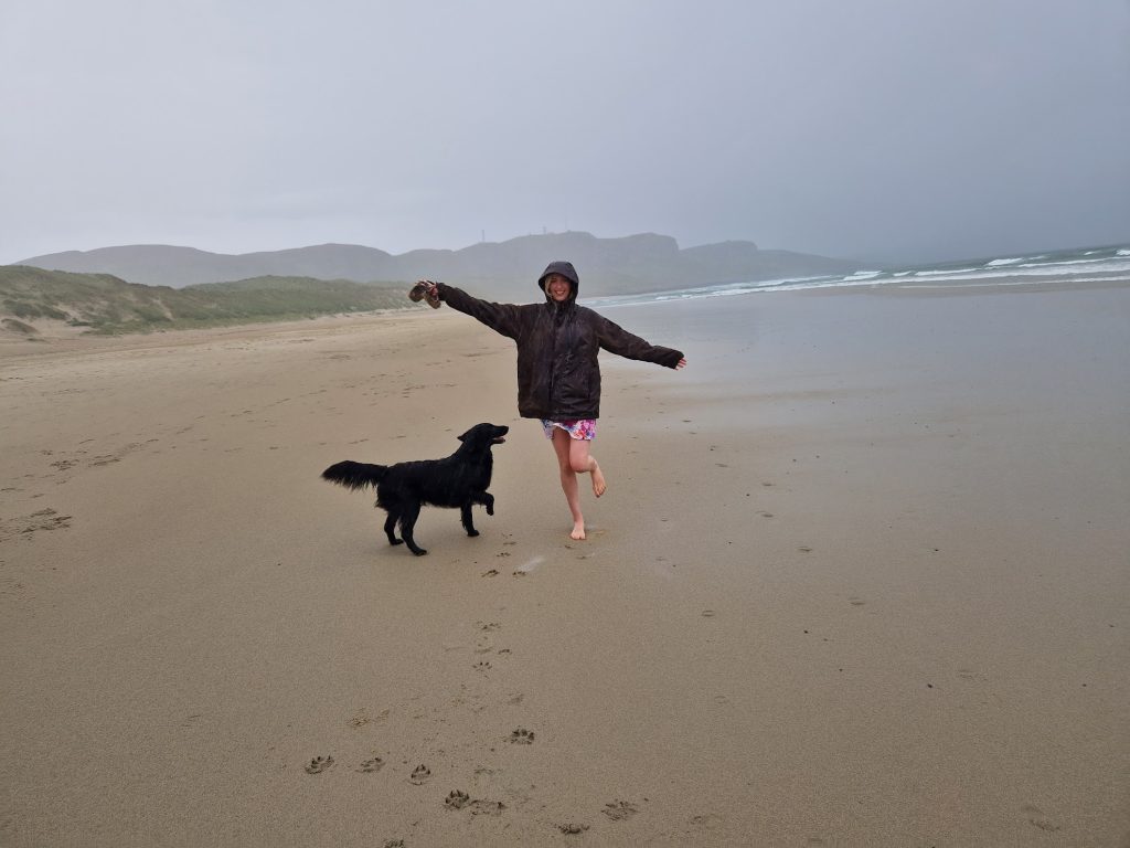 Girl and dog in rain on beach