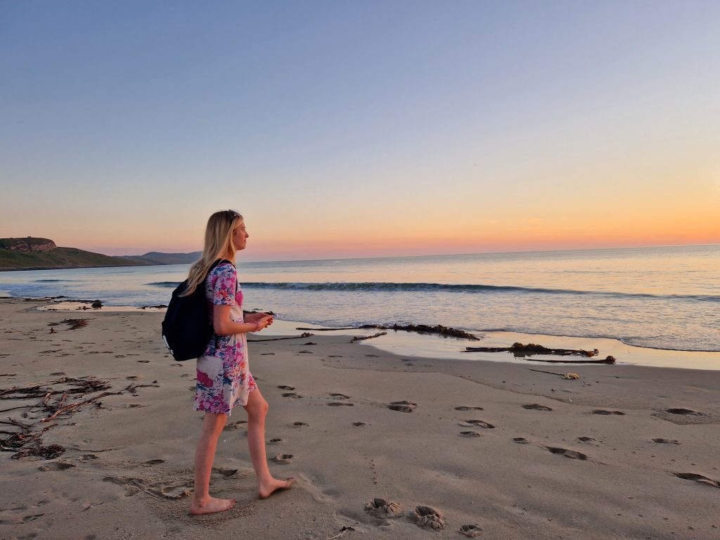 Girl on sandy beach at sunset