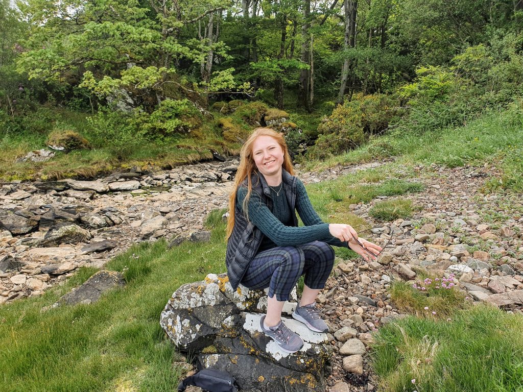 Girl sitting on a rock in the woods.