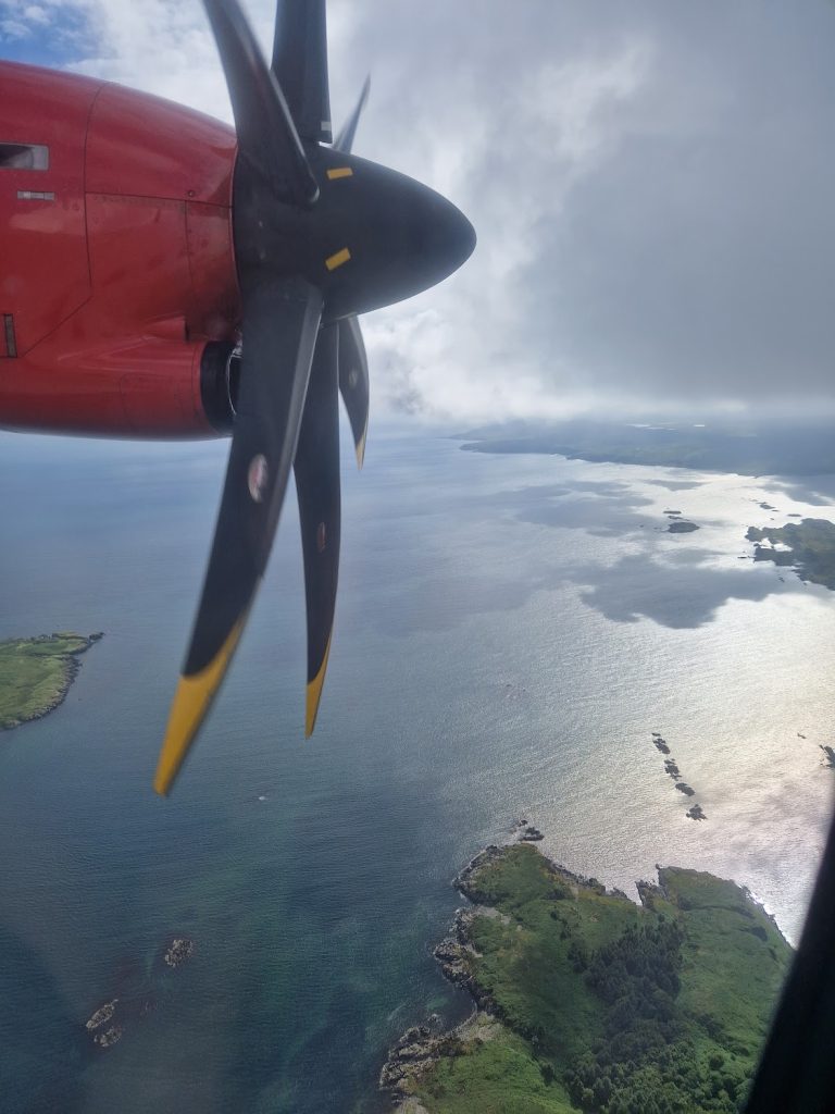 Plane propeller in sky flying over sea.