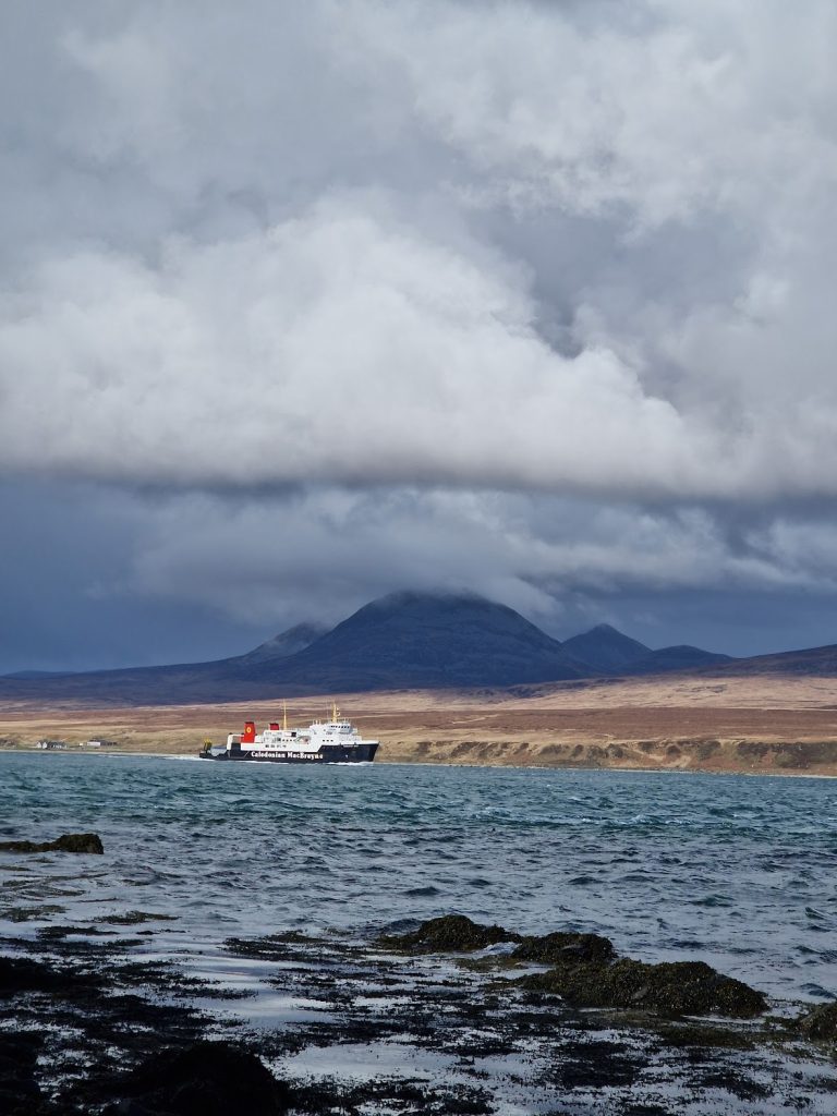 ferry boat sailing in sea, with mountains behind